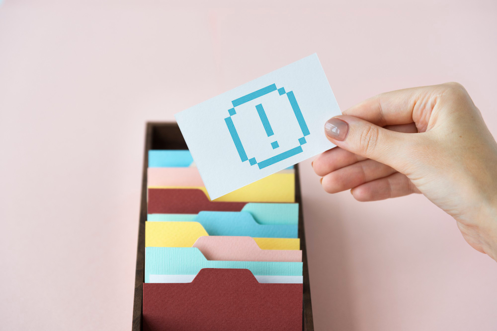 A person holding a piece of paper showing an exclamation point inside a square-typed shape