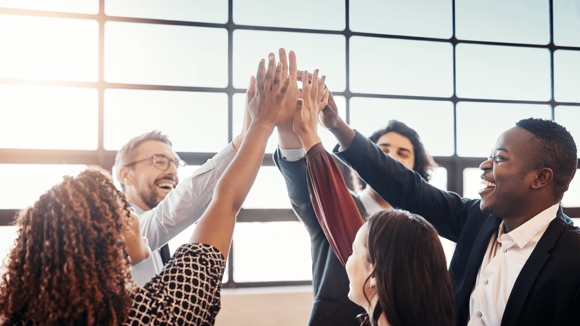 Employees celebrating by putting their hands up in the center together