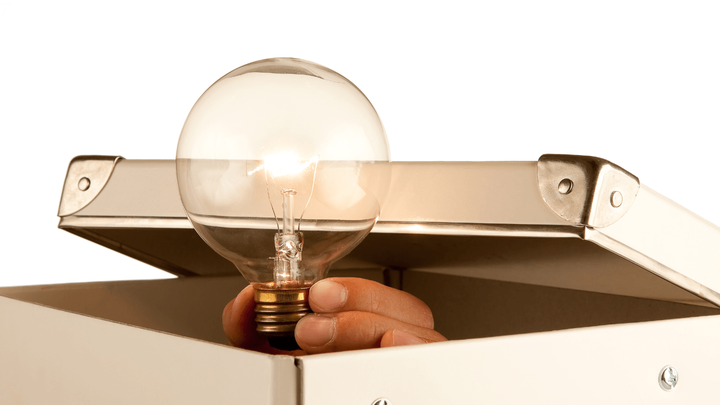 A person's hand holding a light bulb while inside a case