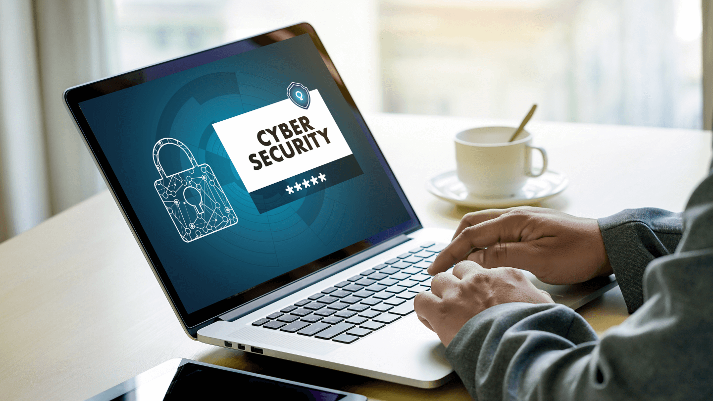 A person using a laptop that displays the word "Cybersecurity"