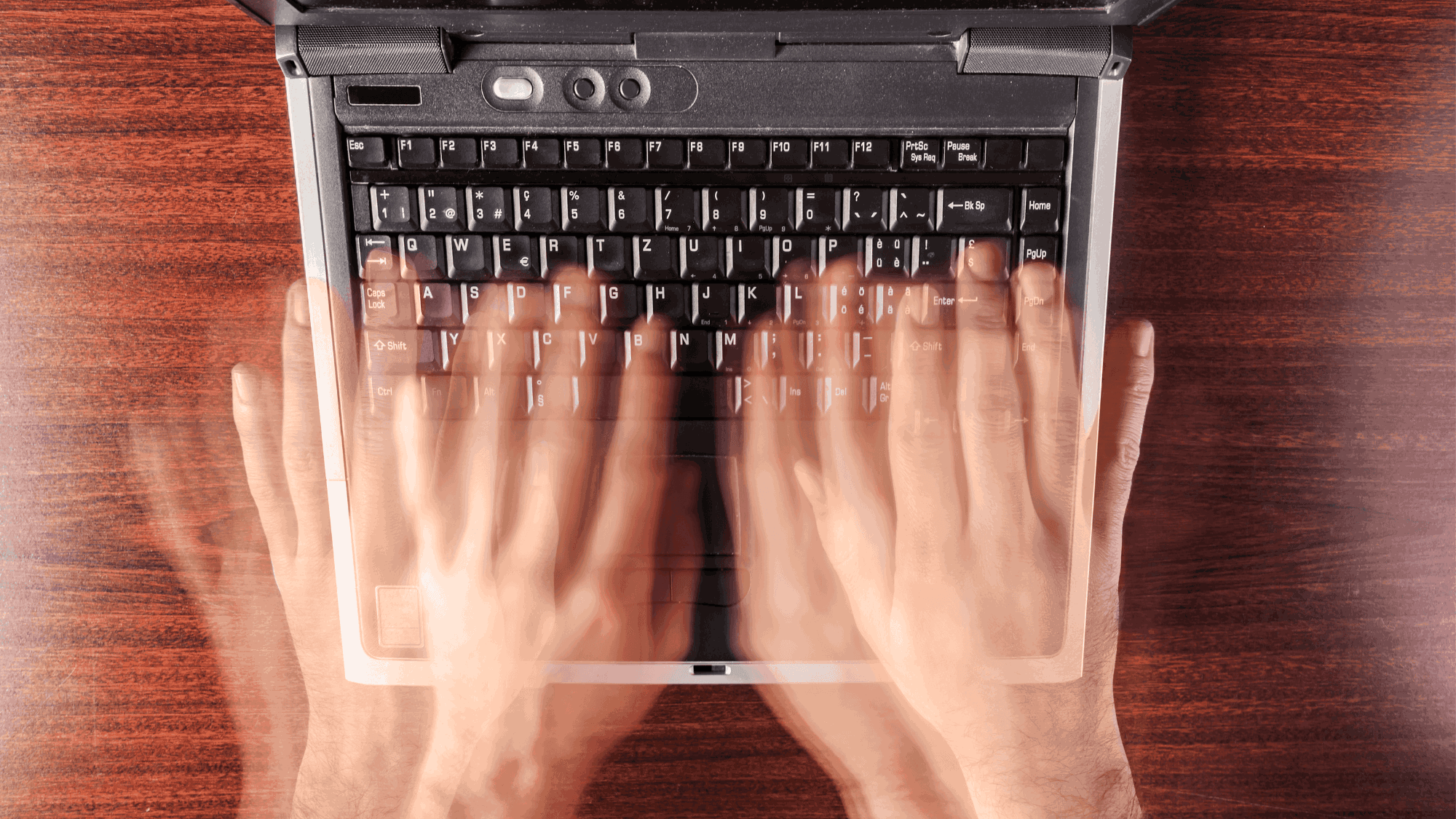 A person typing on a laptop's keyboard with speed