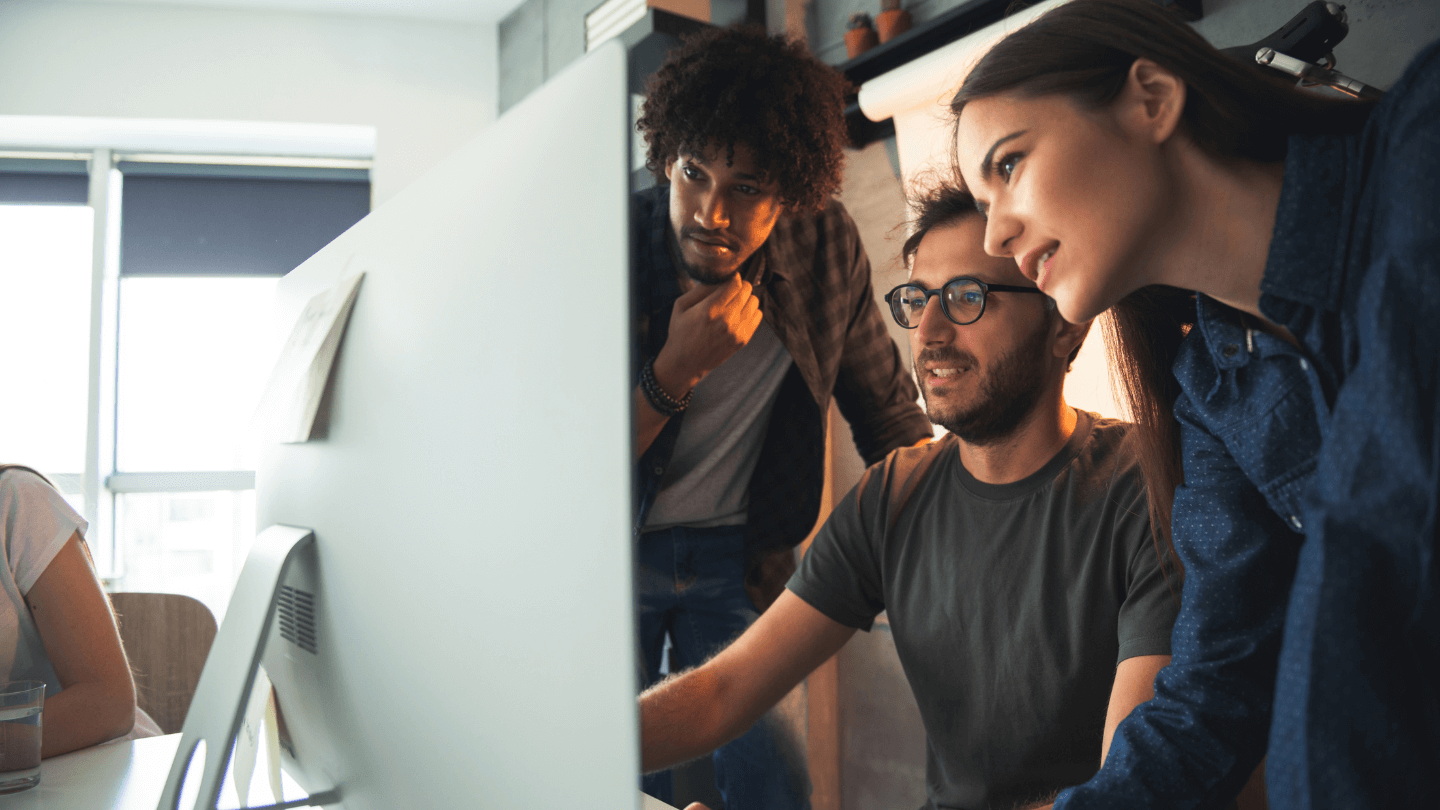 Three people having a conversation while looking at the same monitor