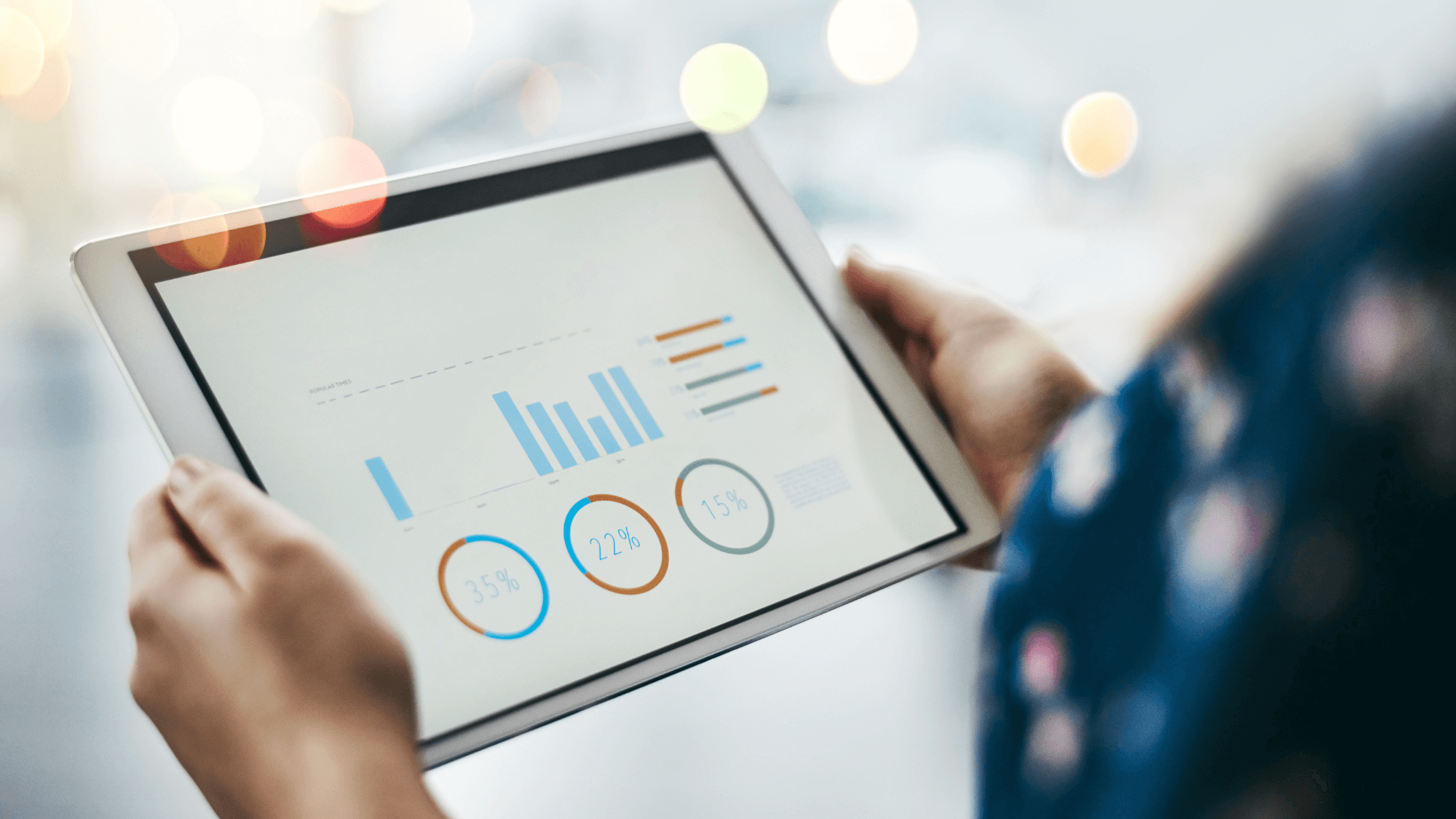 A person holding a tablet displaying different metrics and graphs