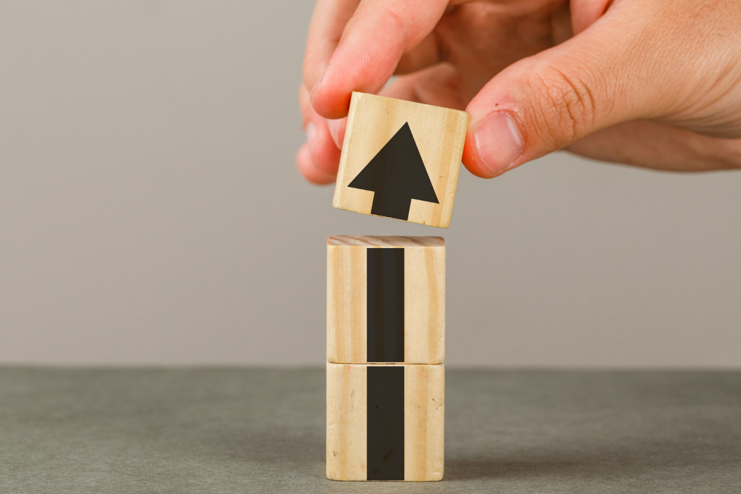 Wooden cubes stacked together with an icon forming an upward arrow