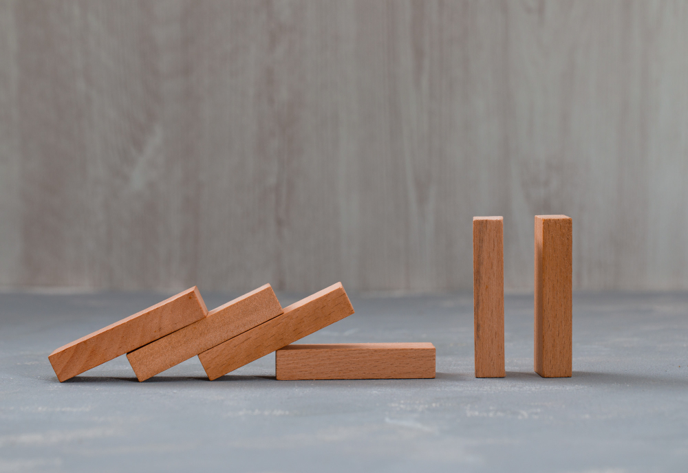 An image of a wooden rectangular blocks forming a domino effect while two are still standing