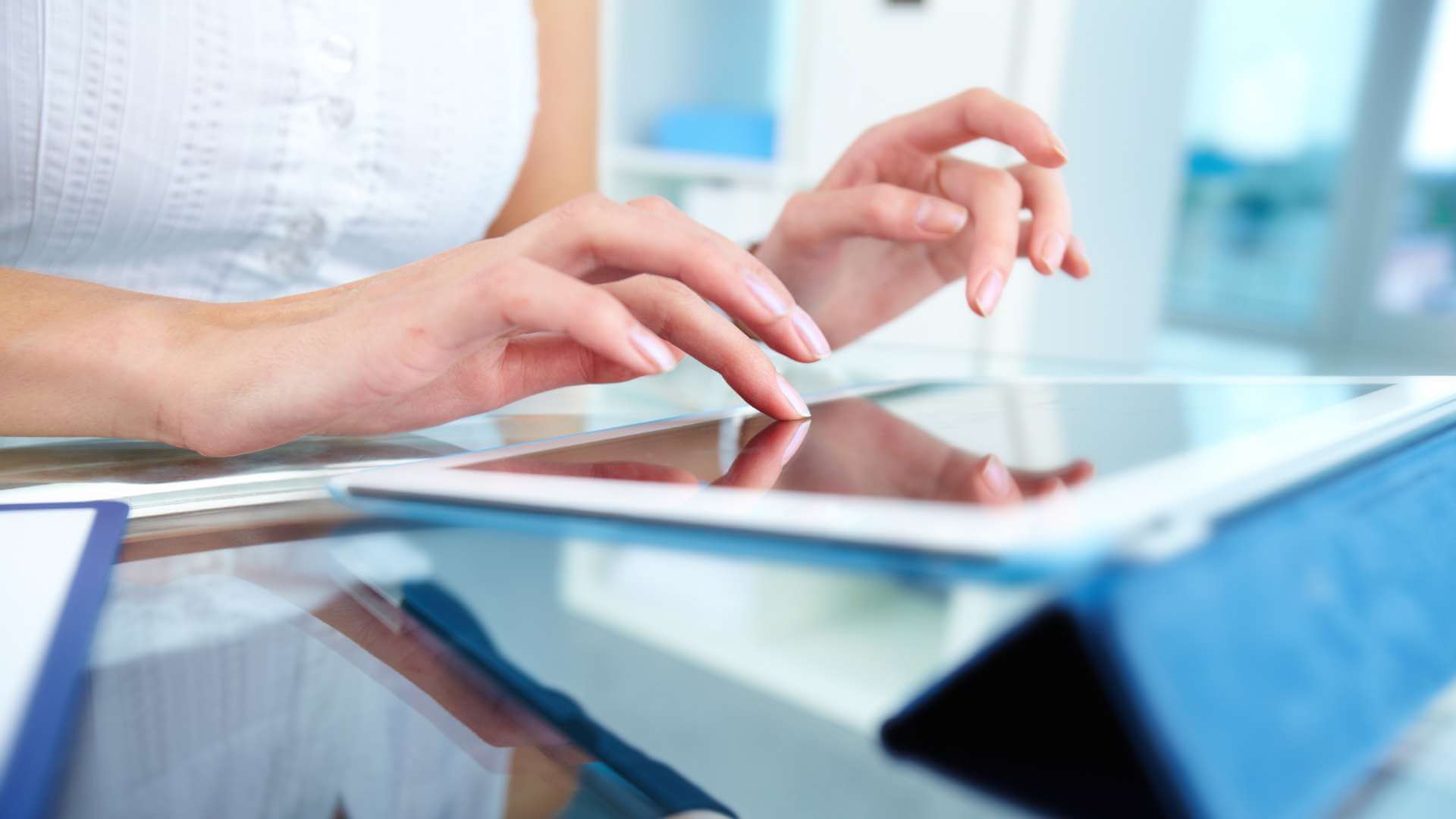 A woman touching her tablet screen while placed on a table