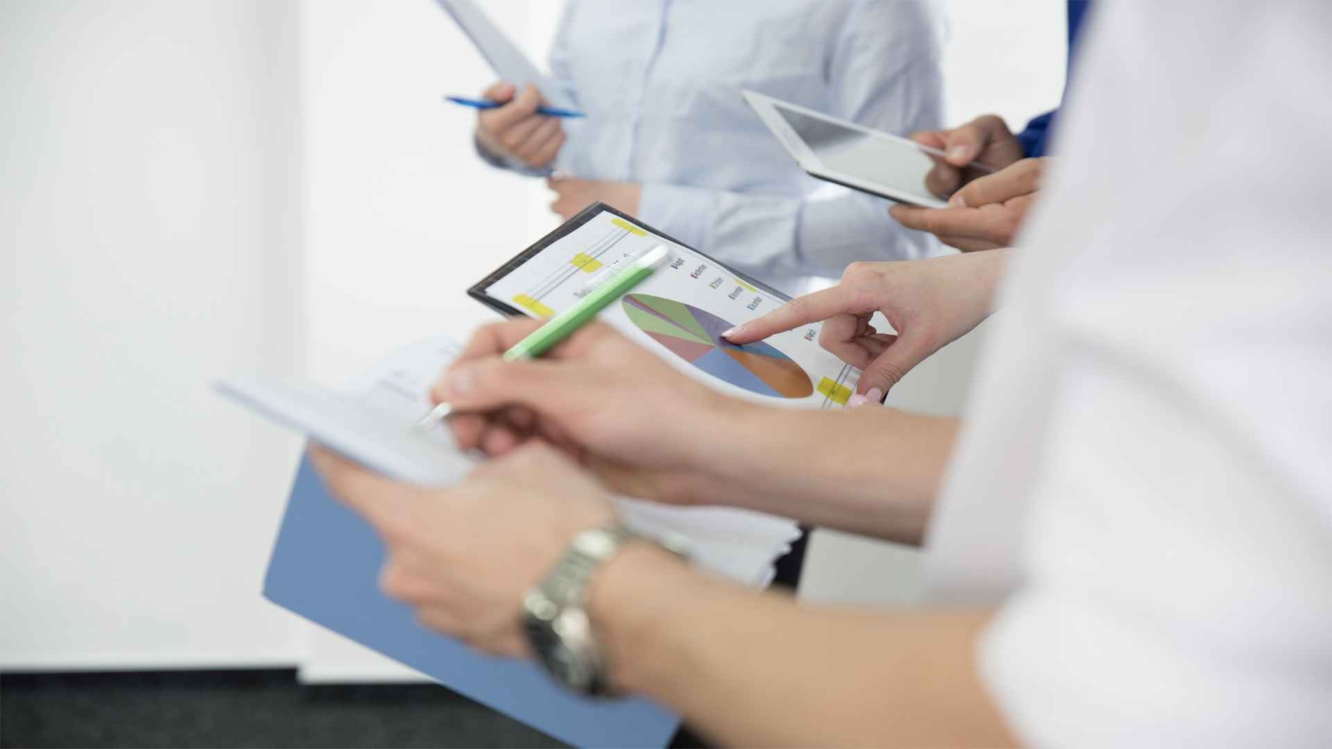 A group of people brainstorming by taking notes and visual graphs